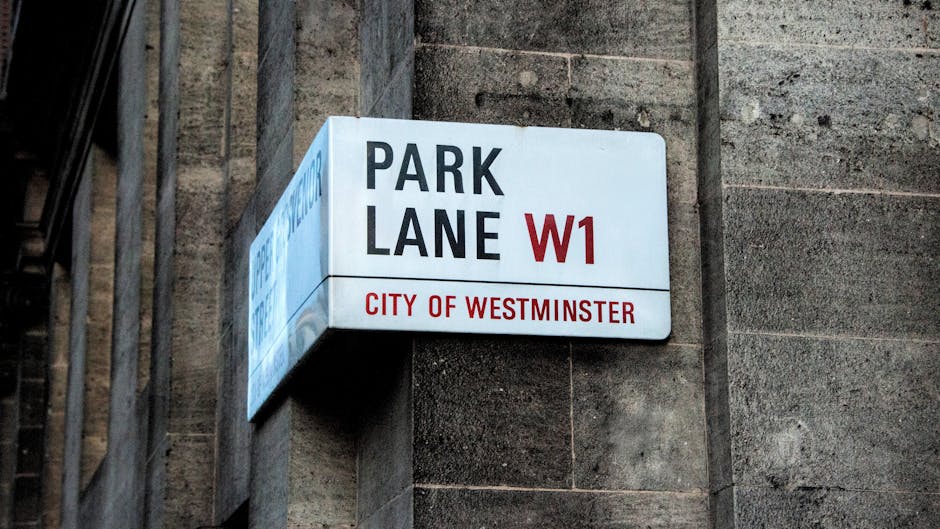 A close-up view of a rectangular street sign affixed to a textured, gray stone wall. The sign displays the words